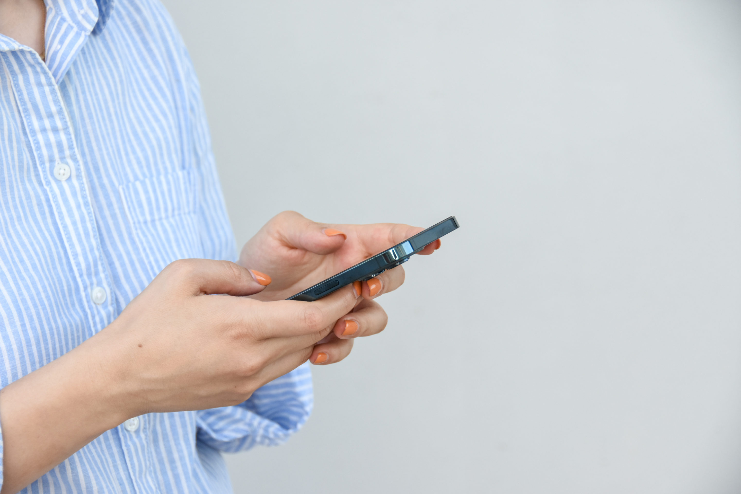 business-woman-holds-smartphone-her-hands-against-white-wall